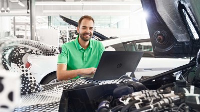Ein Safety-Ingenieur von Bosch Engineering mit Laptop an einem Fahrzeug
